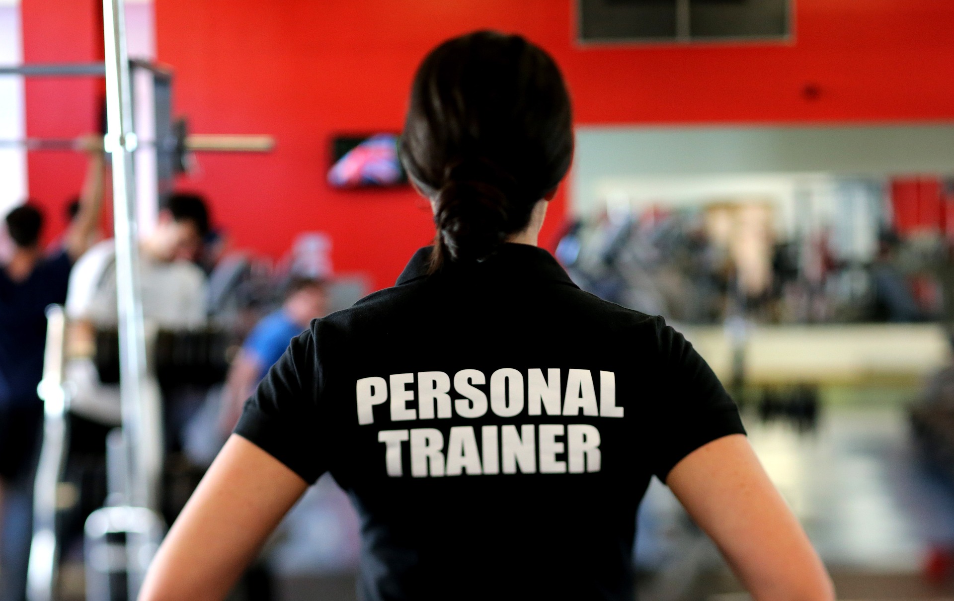 Mulher com camiseta escrito Personal Trainer em uma academia